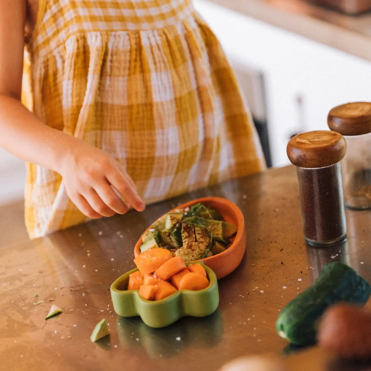Child's hand reaching towards a bowl of food on a table with a blurred background