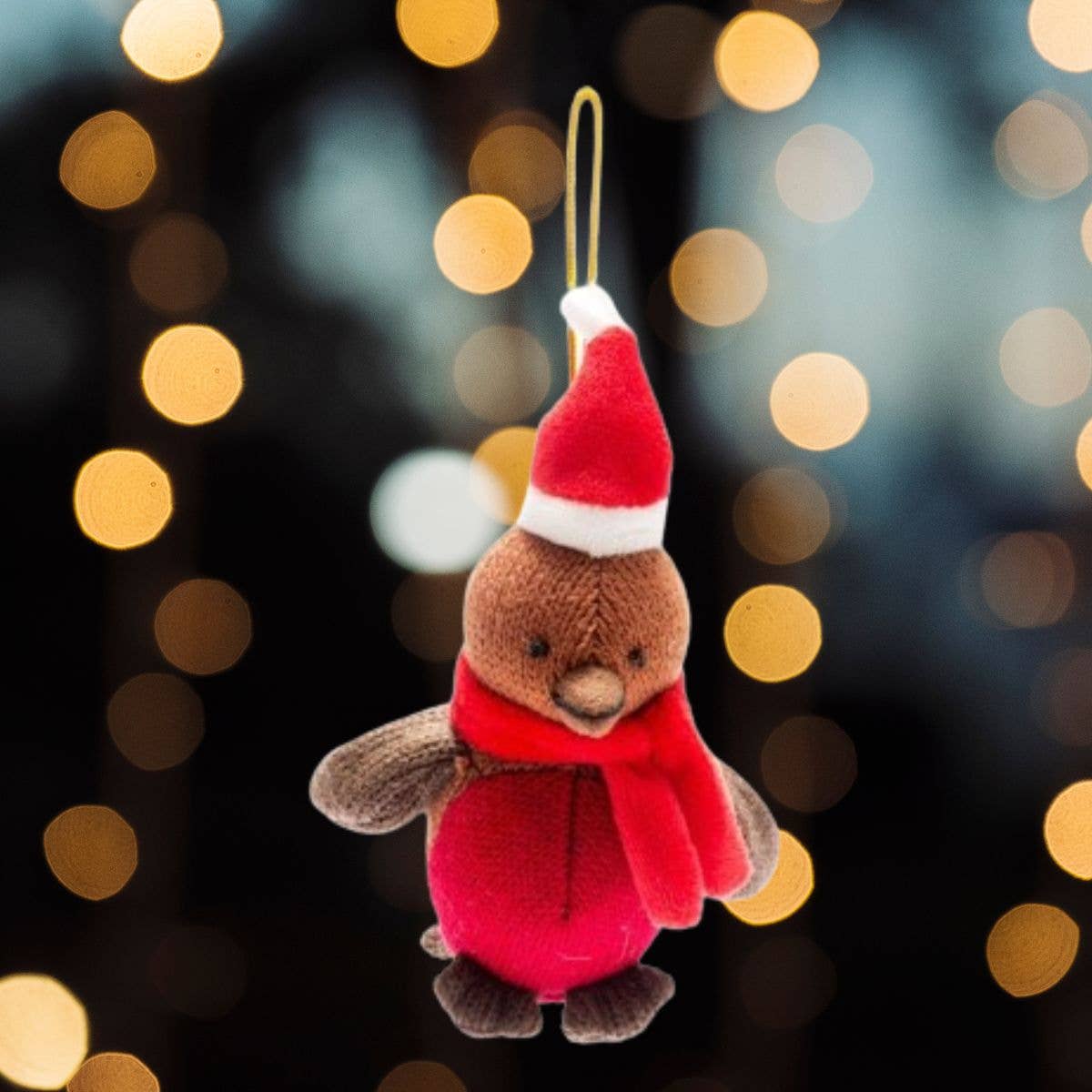 Plush toy robin wearing a Santa hat and scarf against a blurred bokeh light background