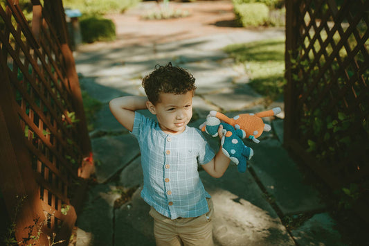 A child holding crochet toys in the shape of a dinosaur rattle
