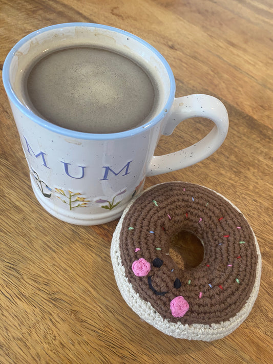 Knitted donut next to a cup of coffee