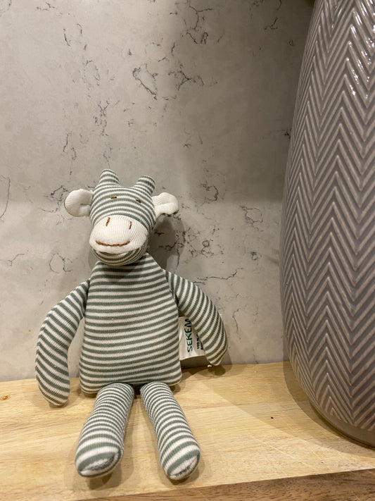 Striped toy giraffe on a wooden surface with a textured wall background