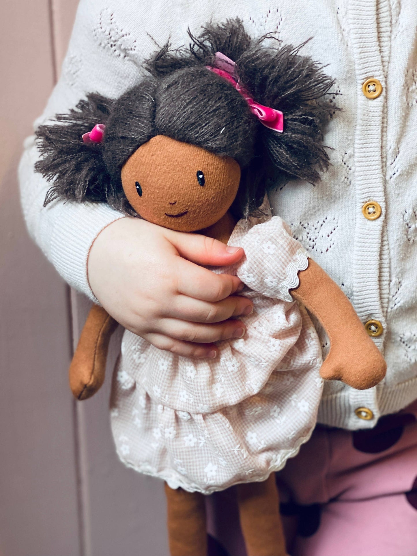 Child holding a doll with dark hair and a white dress.
