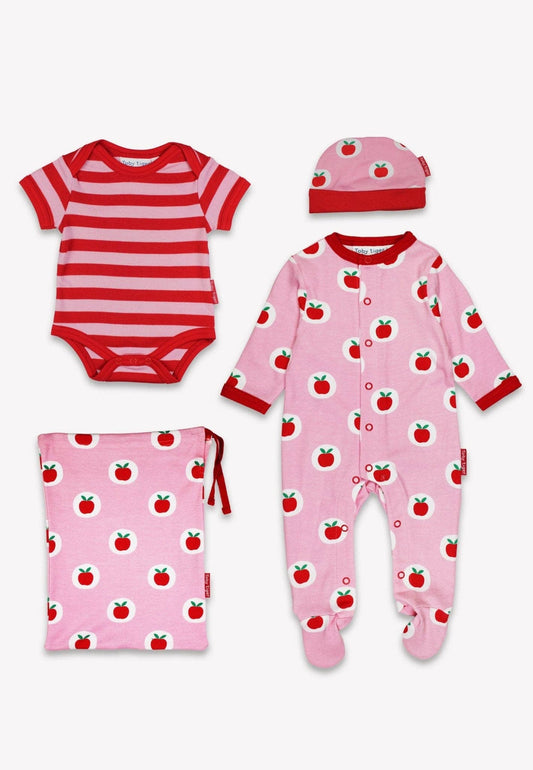 Baby clothing set with striped onesie, pink pajama, hat, and blanket with apple pattern on a white background.
