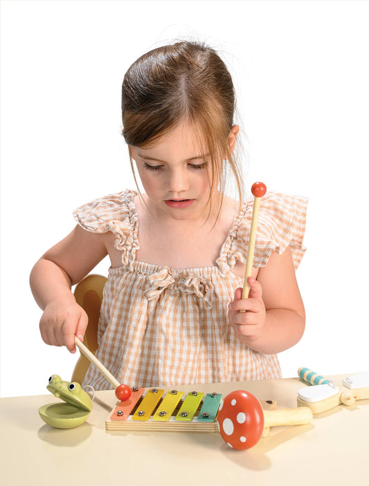 Young girl playing with a colorful wooden toy xylophone on a white background