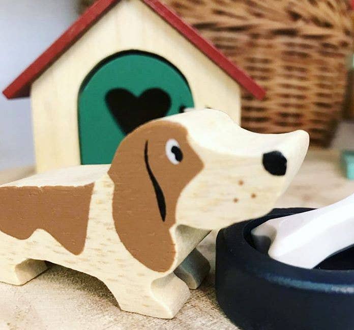 Wooden dog figurine with a doghouse and bowl in the background