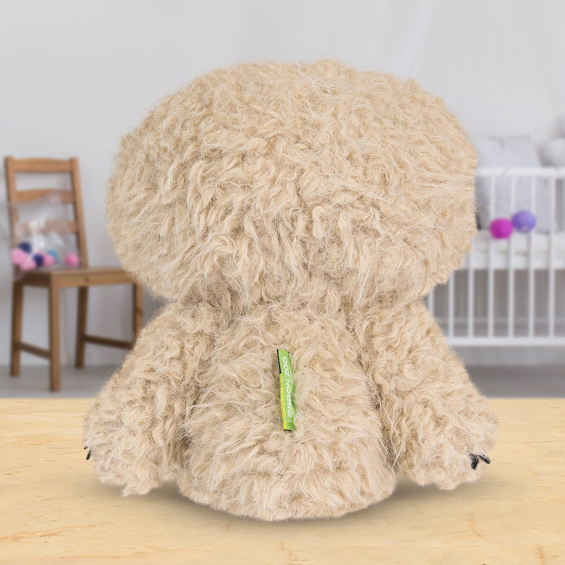 Back of sloth toy with a green tag on a wooden surface, blurred background
