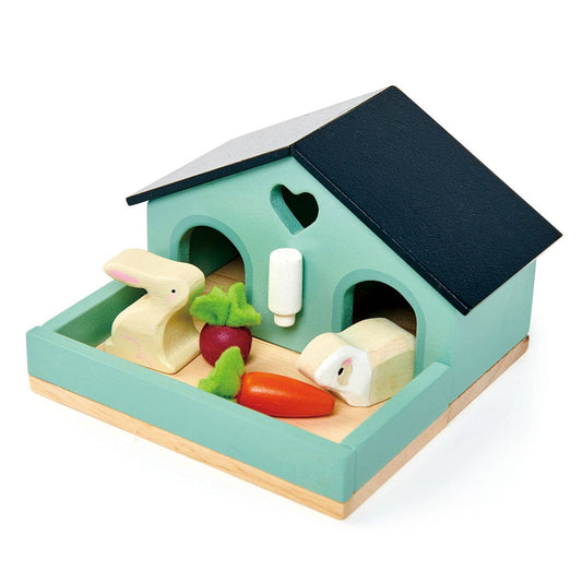 Wooden toy house with rabbit figures and vegetables on a white background