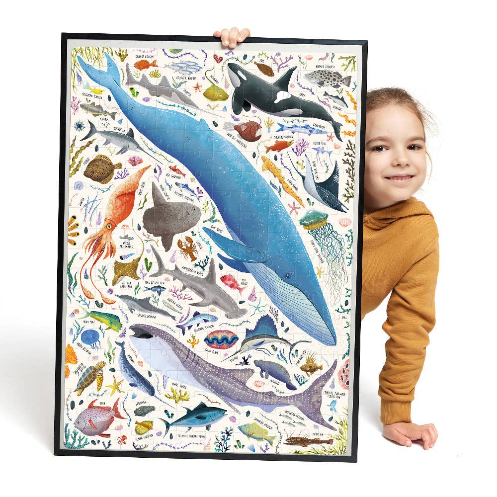 Child holding a large educational poster about marine life with various sea creatures.