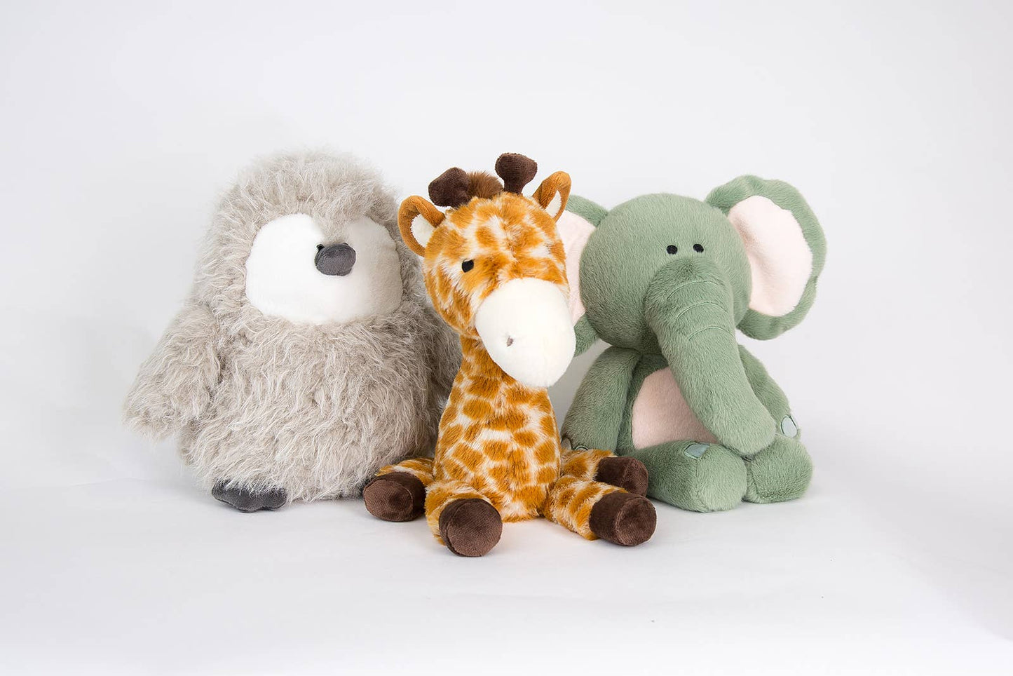 Three plush toys - a gray bear, a giraffe, and a green elephant - on a white background.