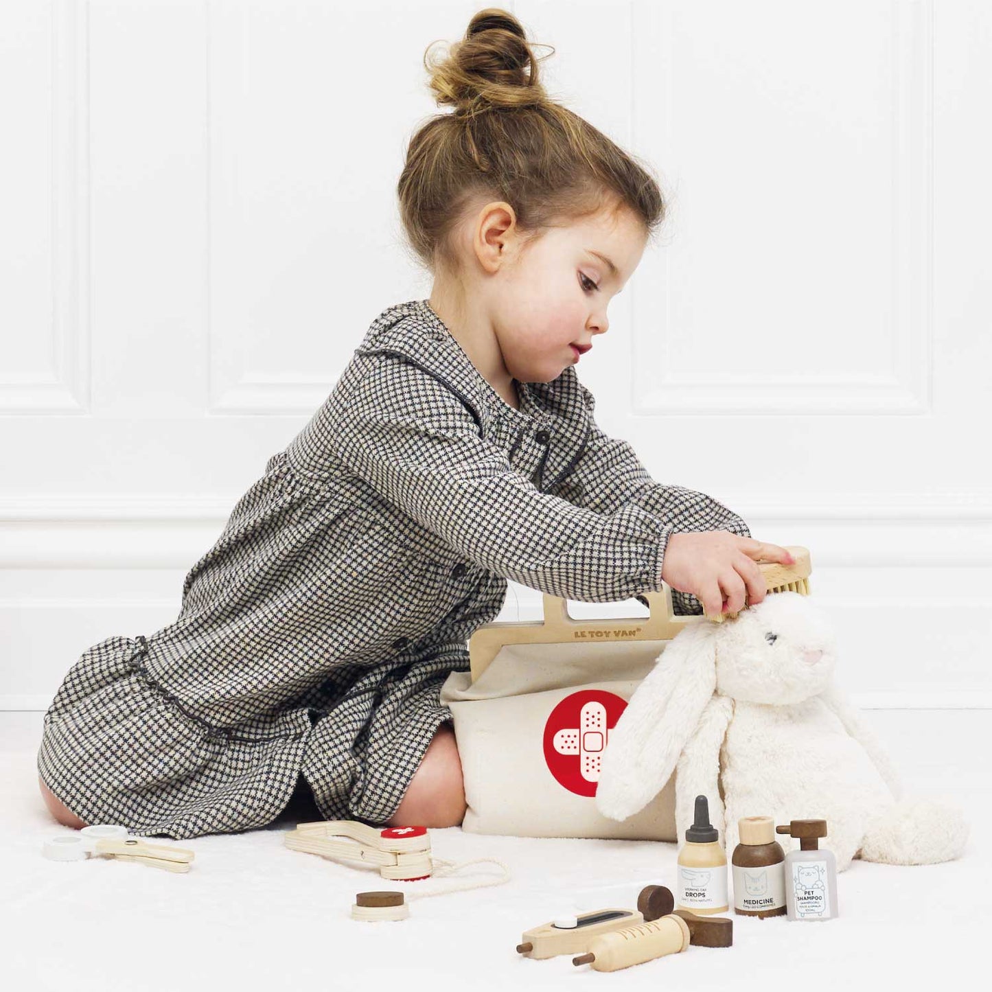 Child playing with toy medical vet set and plush rabbit on a white background