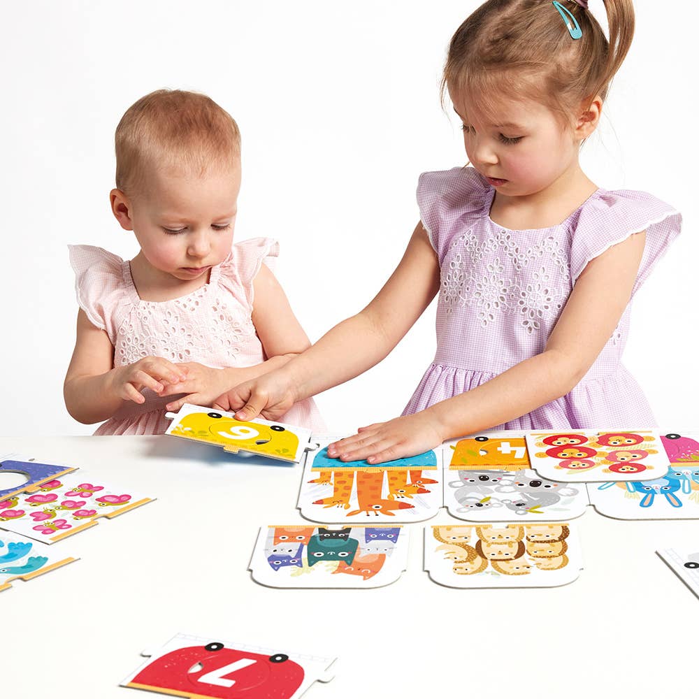 Two young girls playing with educational card games featuring animals and numbers.