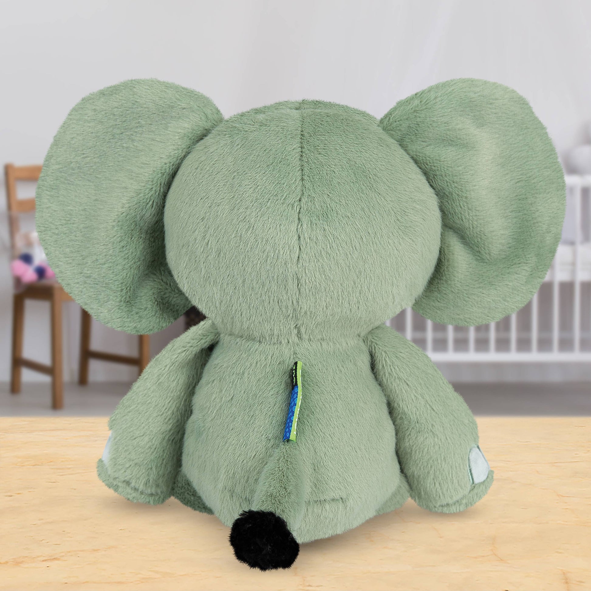 Green plush elephant toy on a wooden surface with a blurred background