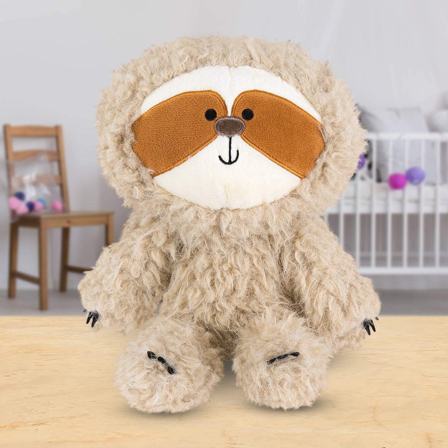Plush toy sloth  on a wooden surface in a room setting
