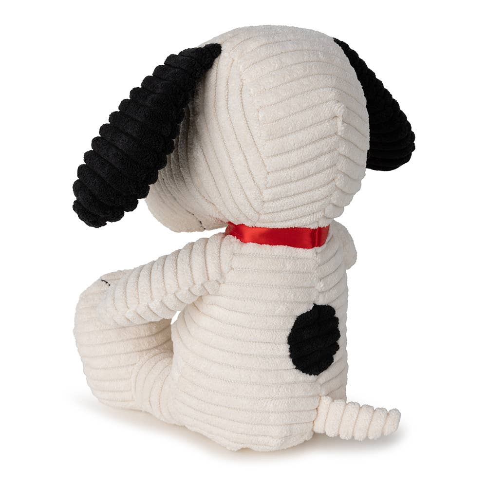 Stuffed Snoopy dog toy with black ears and paws, wearing a red ribbon on a white background
