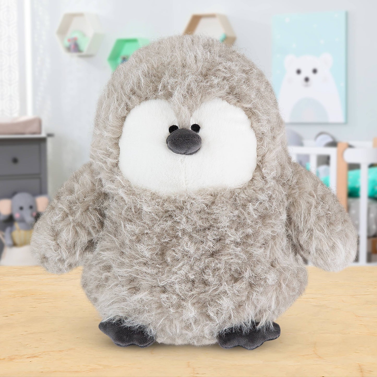 Plush toy penguin on a wooden surface with a blurred background