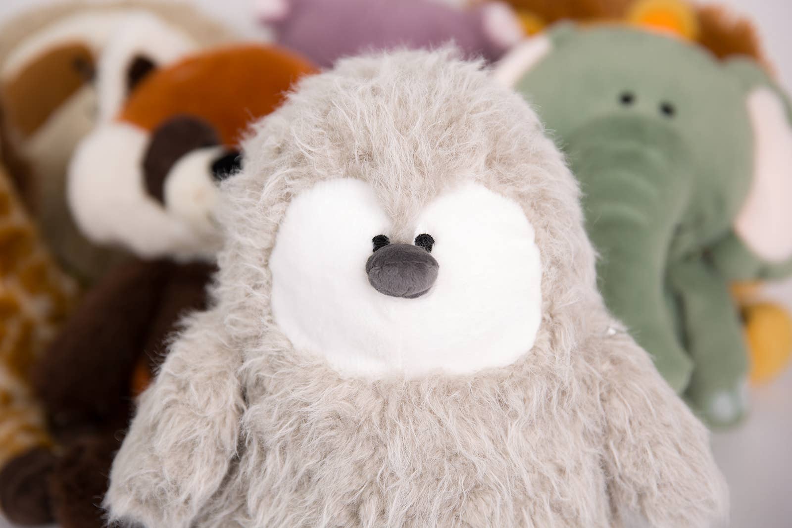 Close-up of a plush toy with a focus on its face, surrounded by other plush toys in the background.