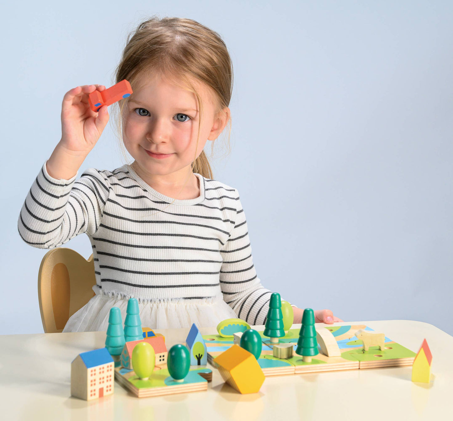 Young girl playing with a wooden toy set on a light blue background