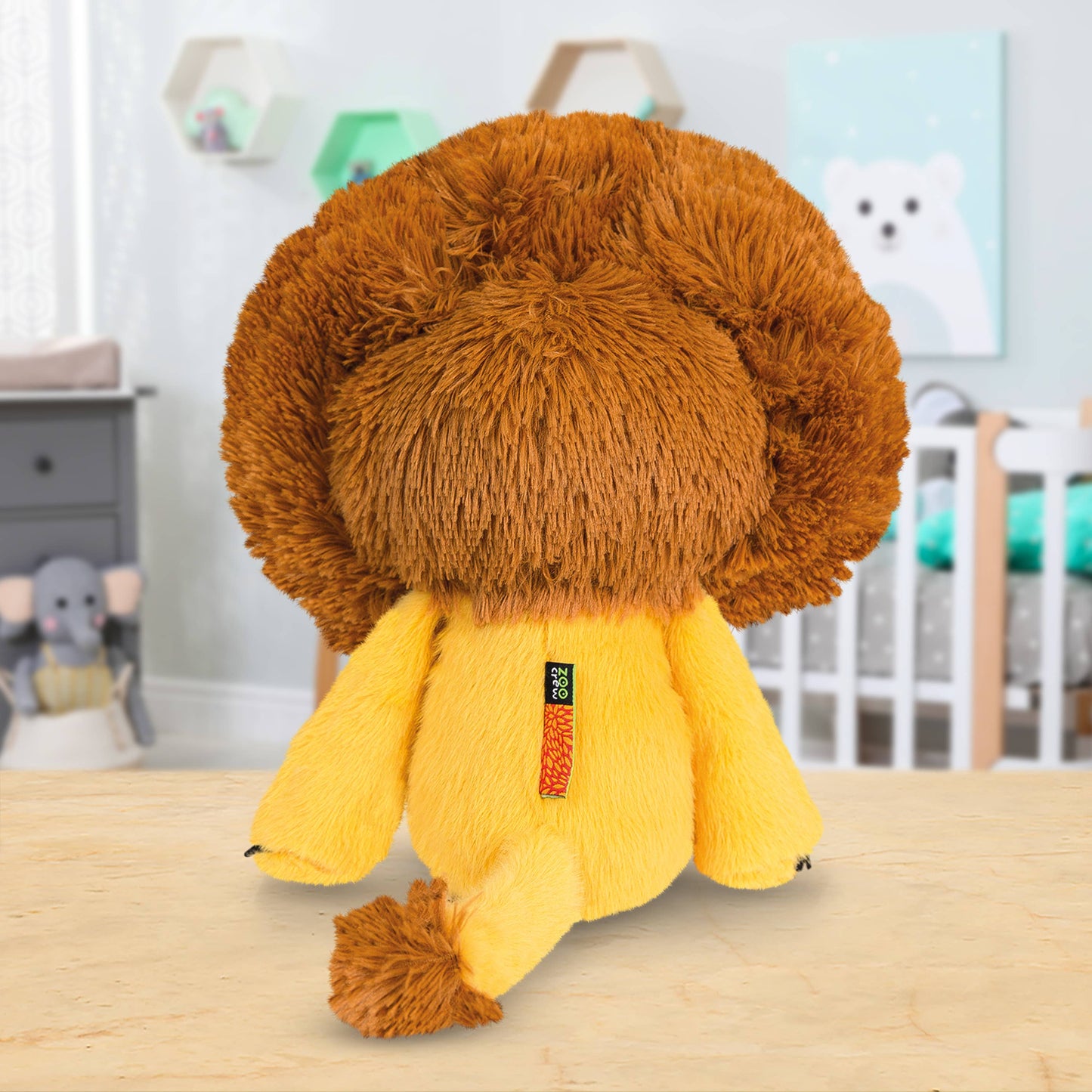 Plush lion toy on a wooden surface with a blurred background of a room.