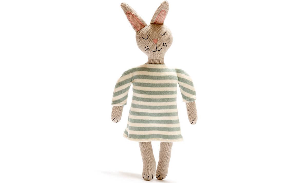 Knitted toy rabbit wearing a striped dress on a white background