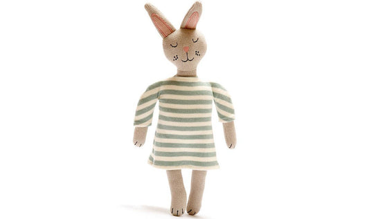 Knitted toy rabbit wearing a striped dress on a white background