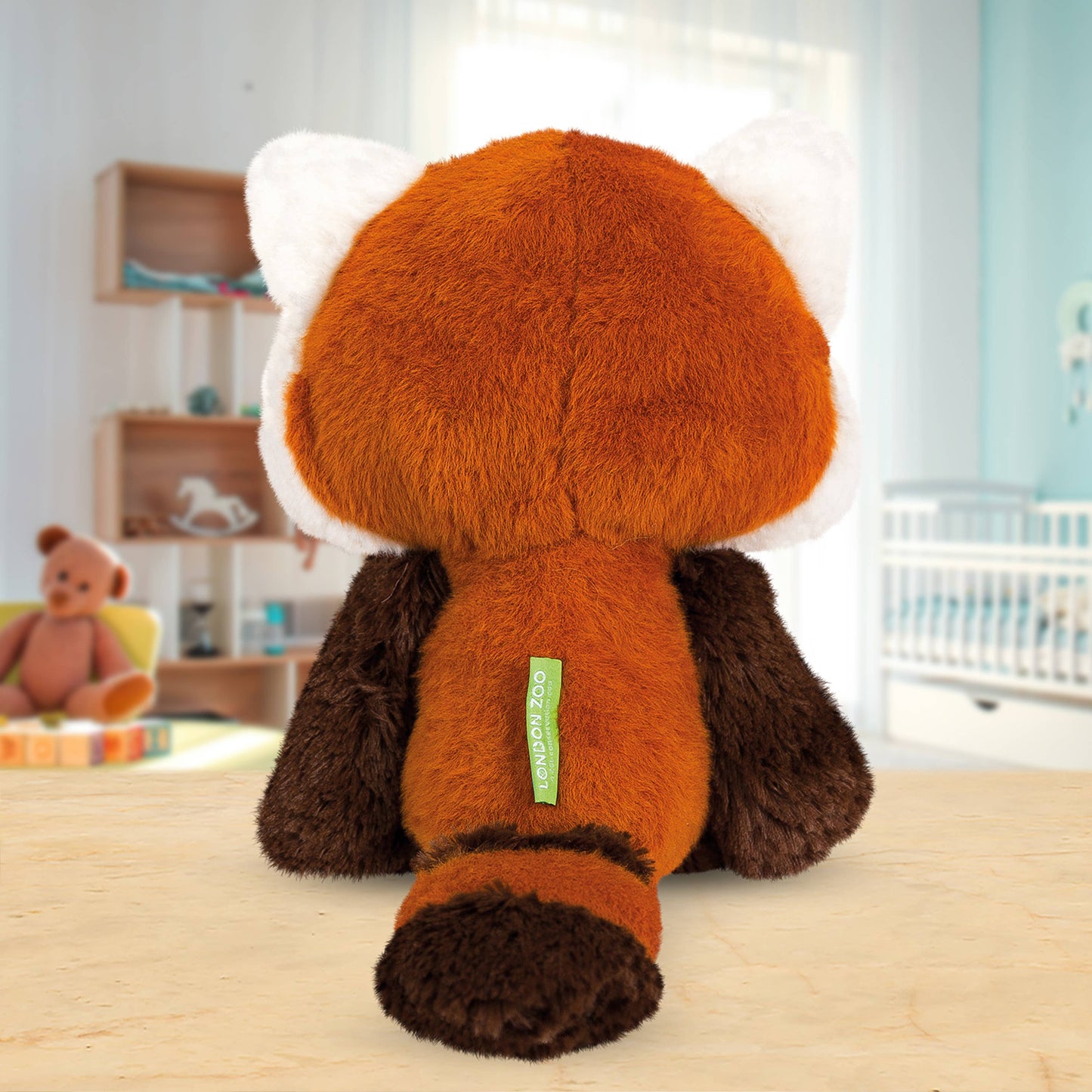 Back of plush toy with a green tag on a wooden surface in a room with shelves and another toy in the background.