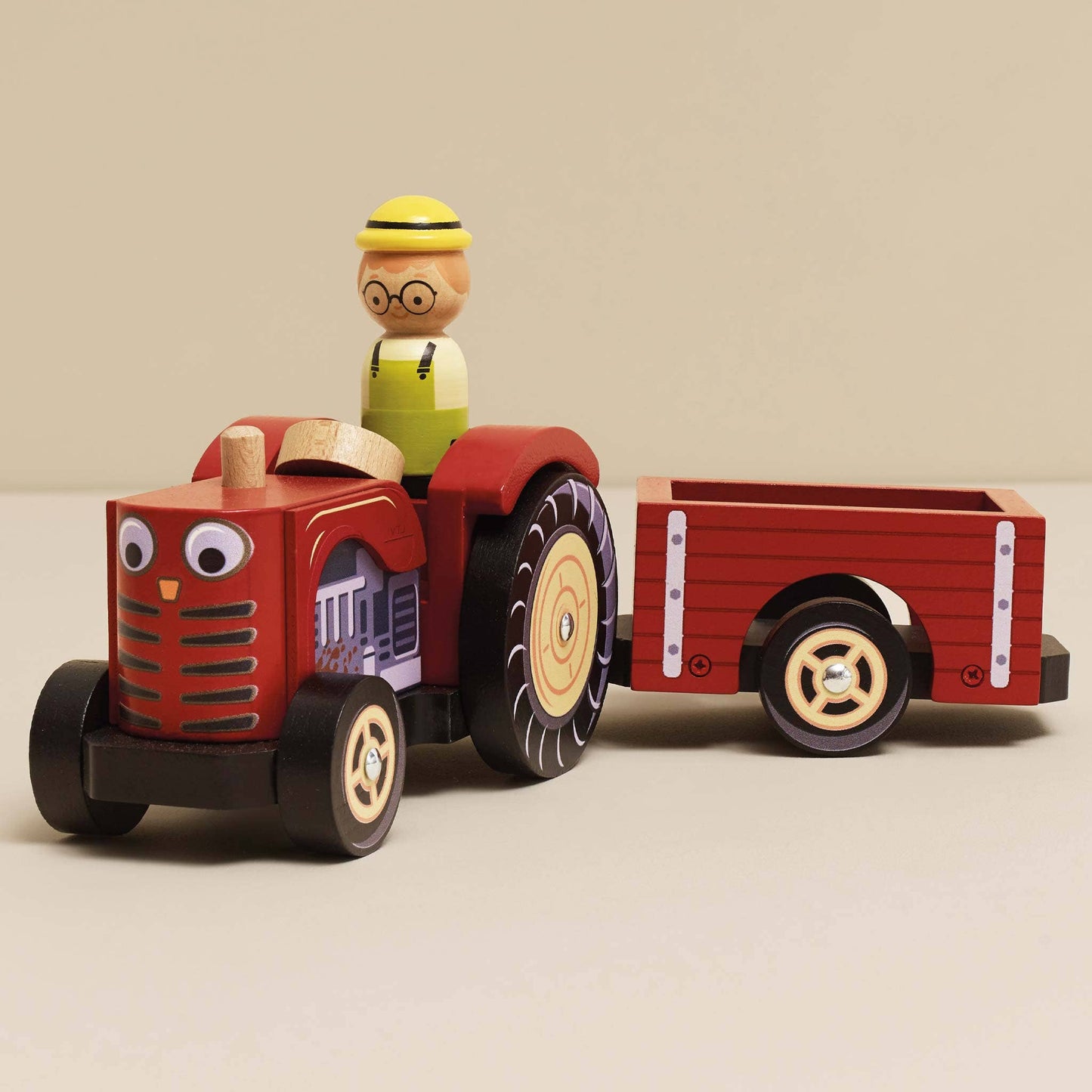 Wooden toy tractor with a driver figure on a beige background