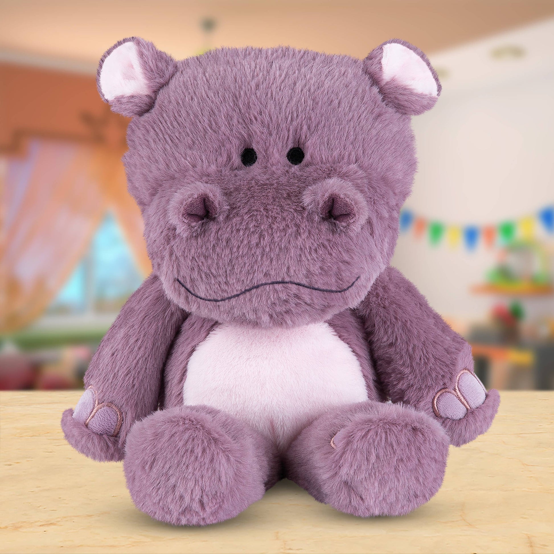 Purple hippo plush toy on a wooden surface with a colorful background