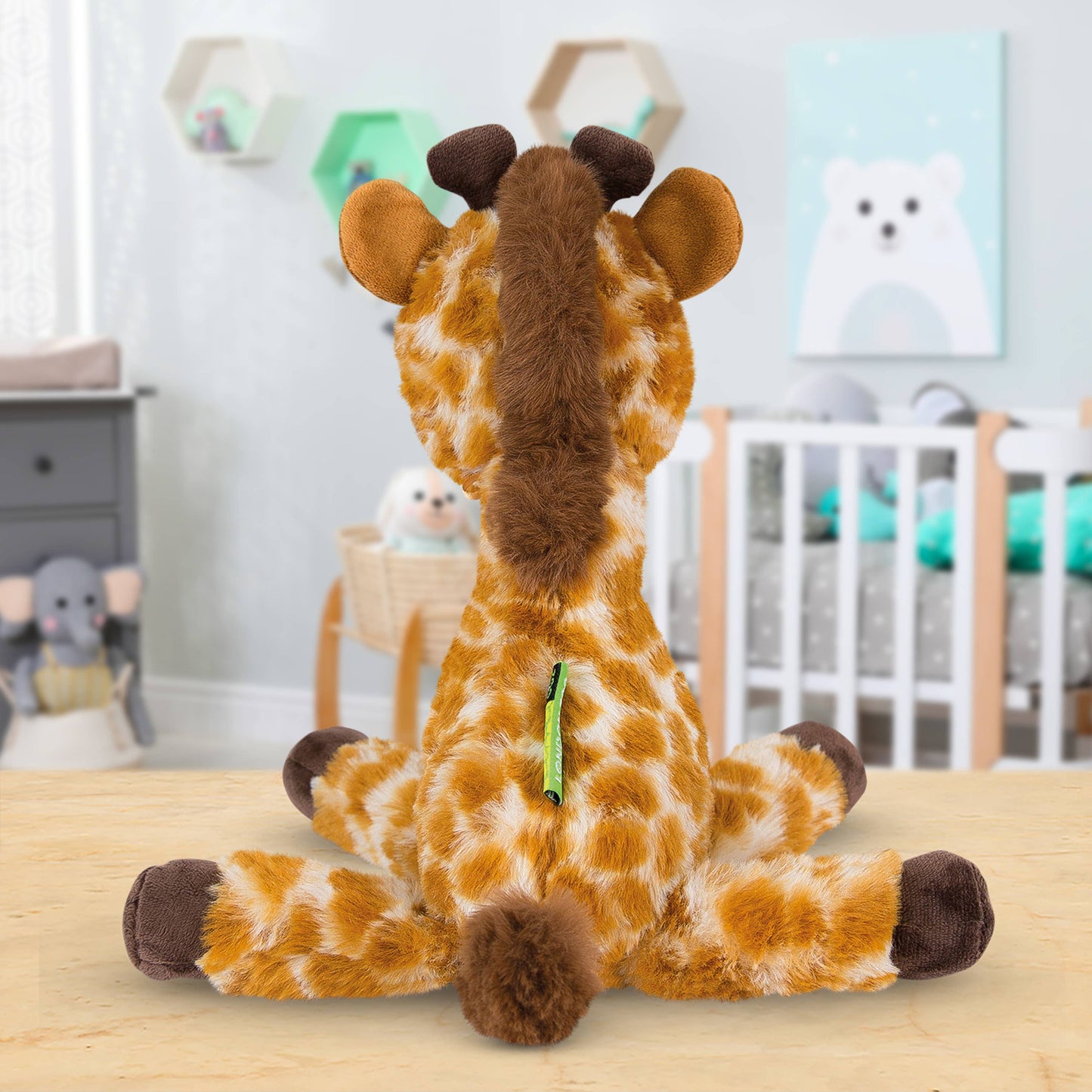 Plush giraffe toy on a wooden surface with a nursery in the background