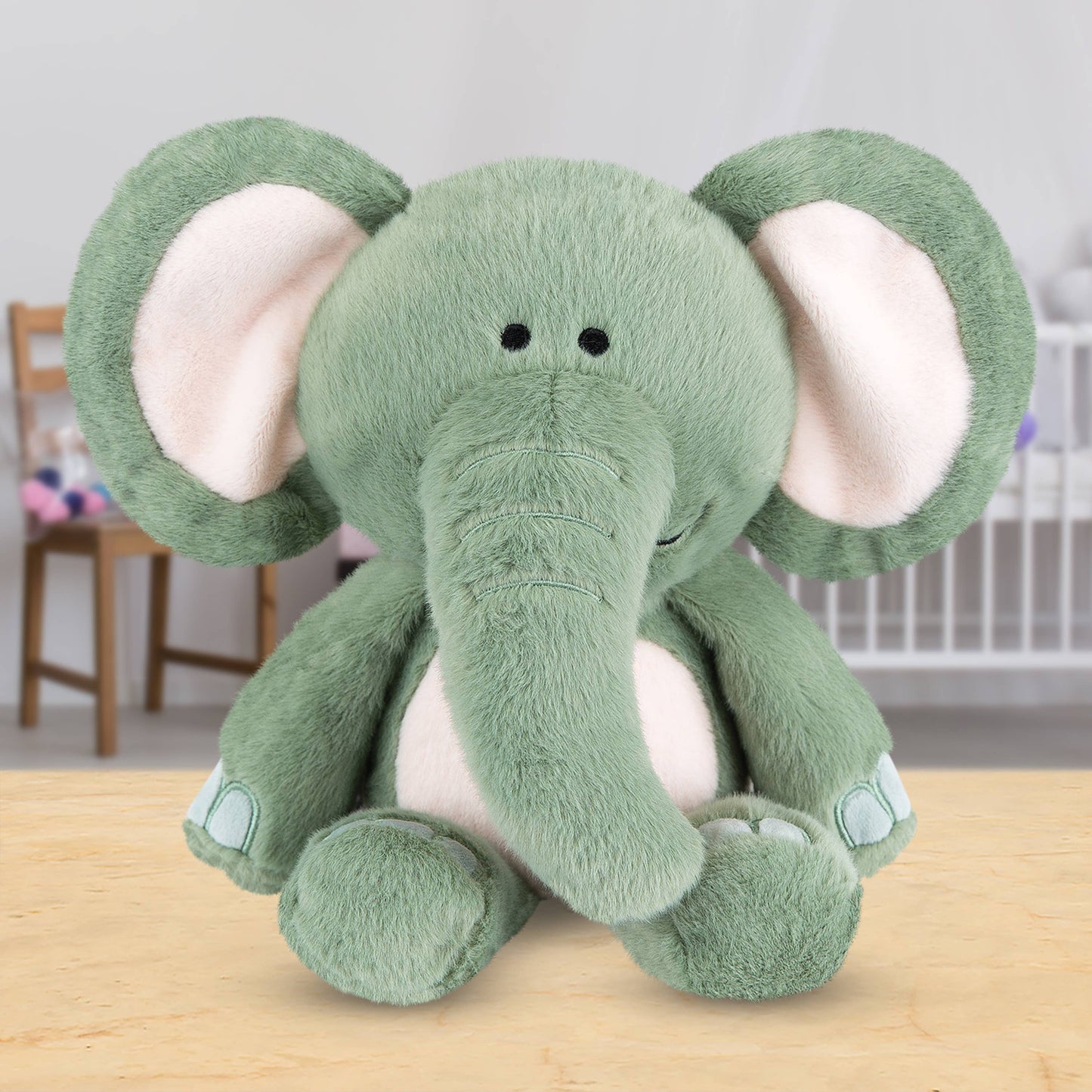 Grey plush elephant toy on a wooden surface with a blurred background