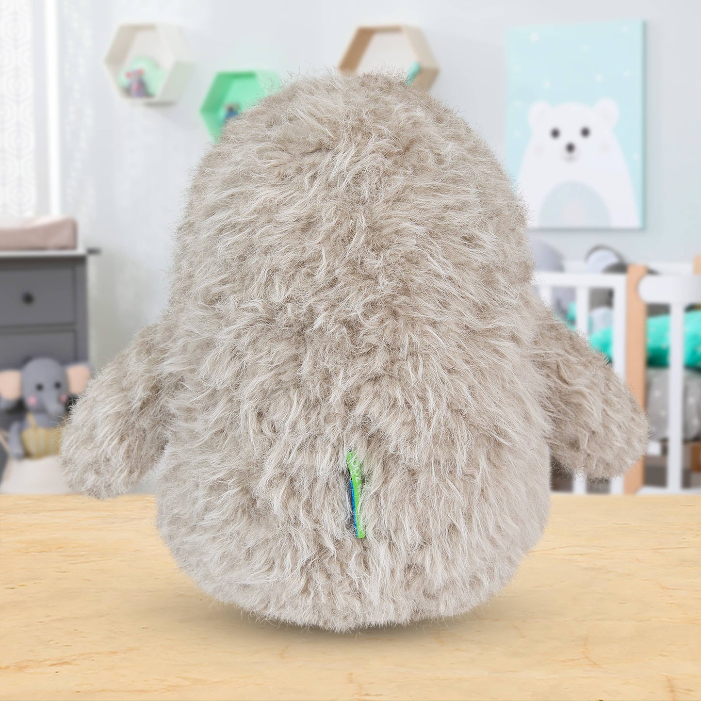 Fluffy gray pillow on a wooden surface with a blurred background of a room.