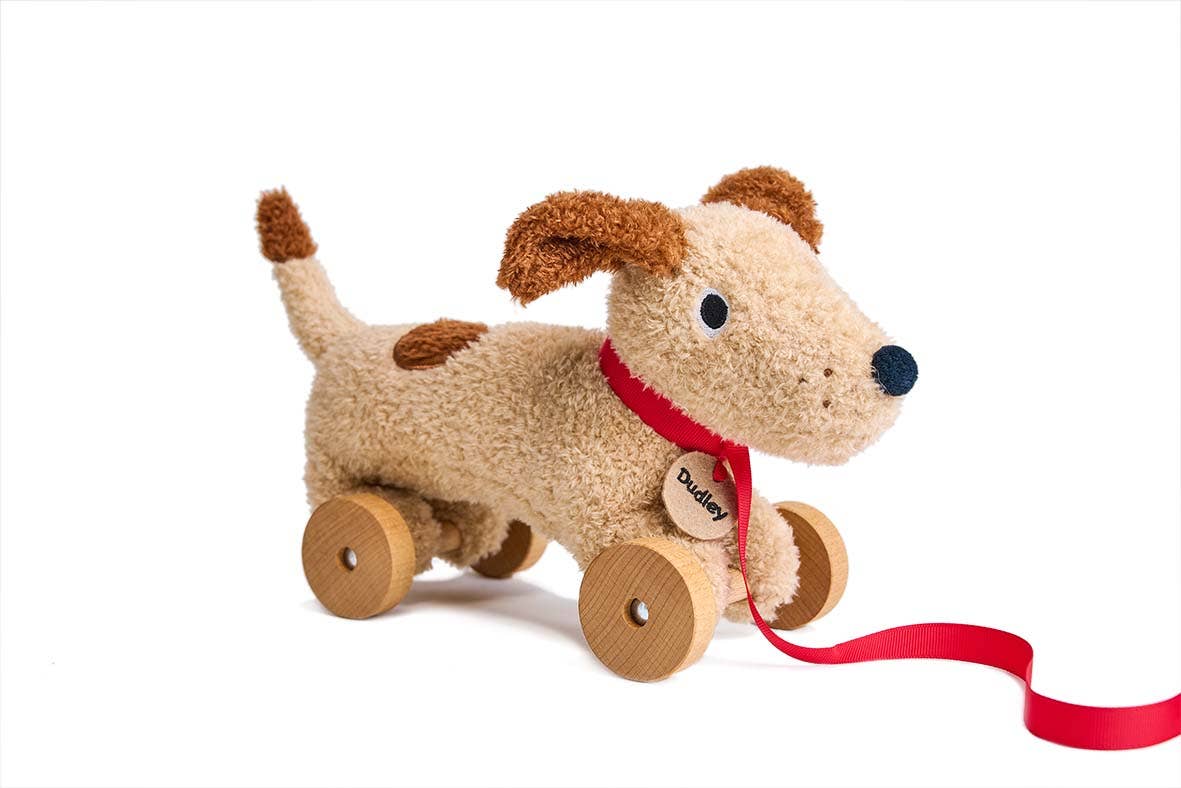 Plush dog toy with wheels and a red ribbon on a white background