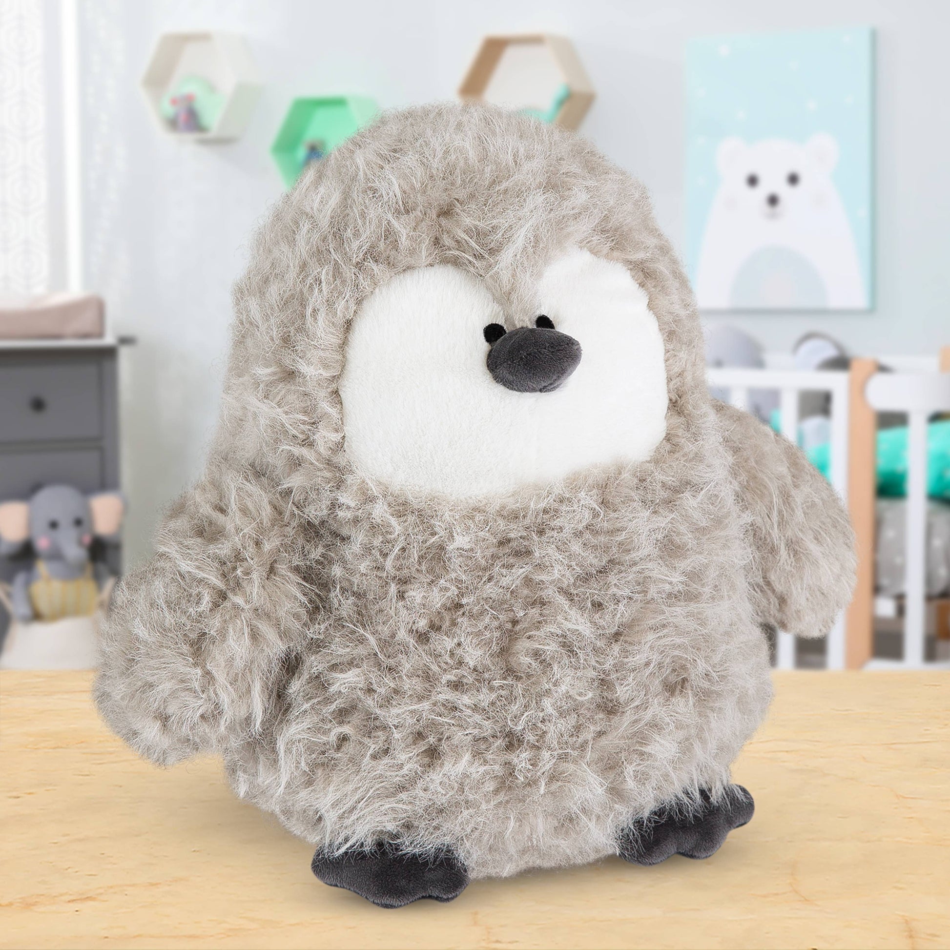Plush toy penguin on a wooden surface with a baby room in the background