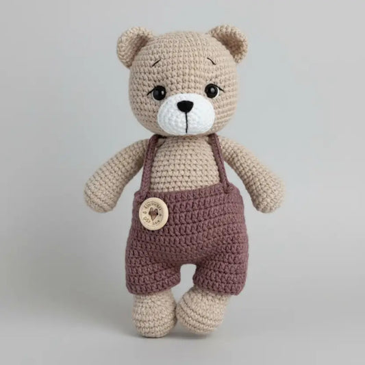 Cream teddy bear wearing brown clothing 