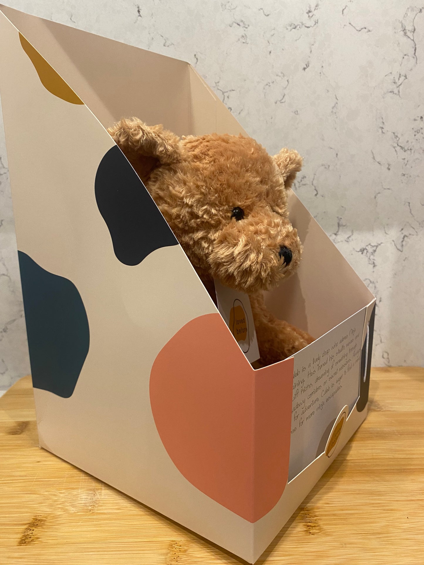 Teddy bear peeking out from a decorative box 