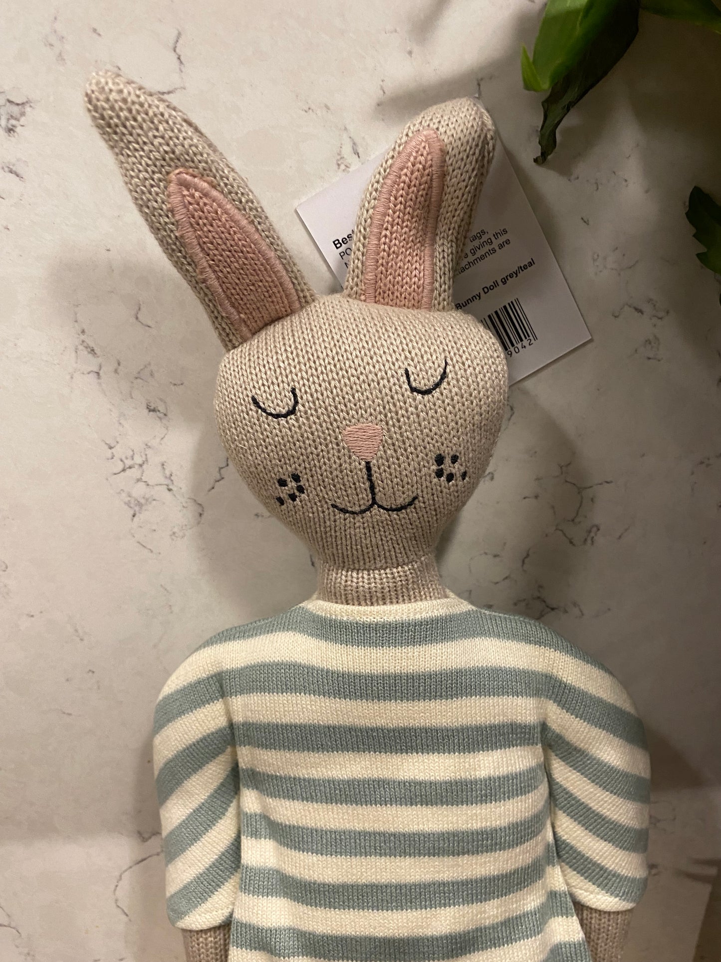 Knitted rabbit toy with striped tail on a light surface