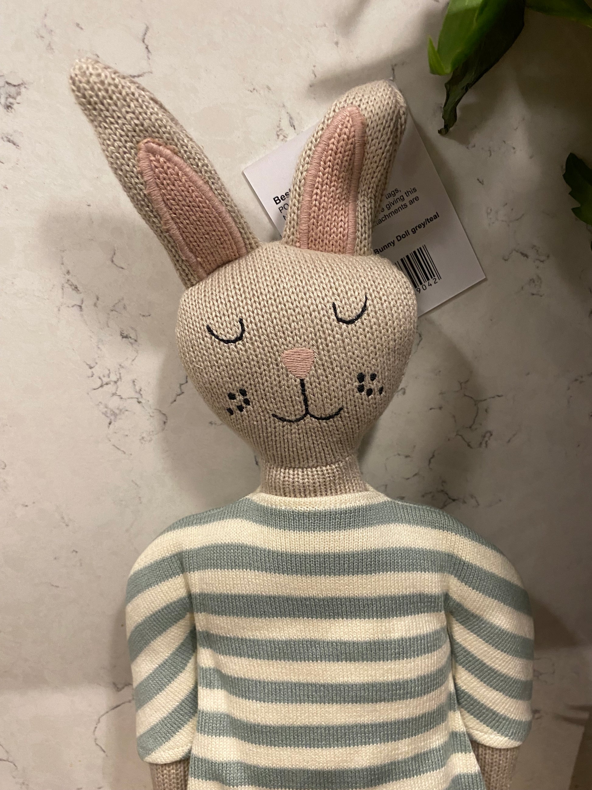 Knitted rabbit toy with striped tail on a light surface