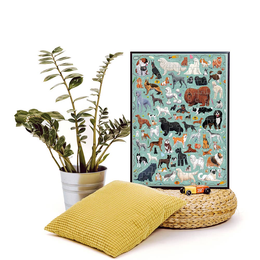 Framed poster of various dog illustrations next to a plant and yellow cushion on a white background