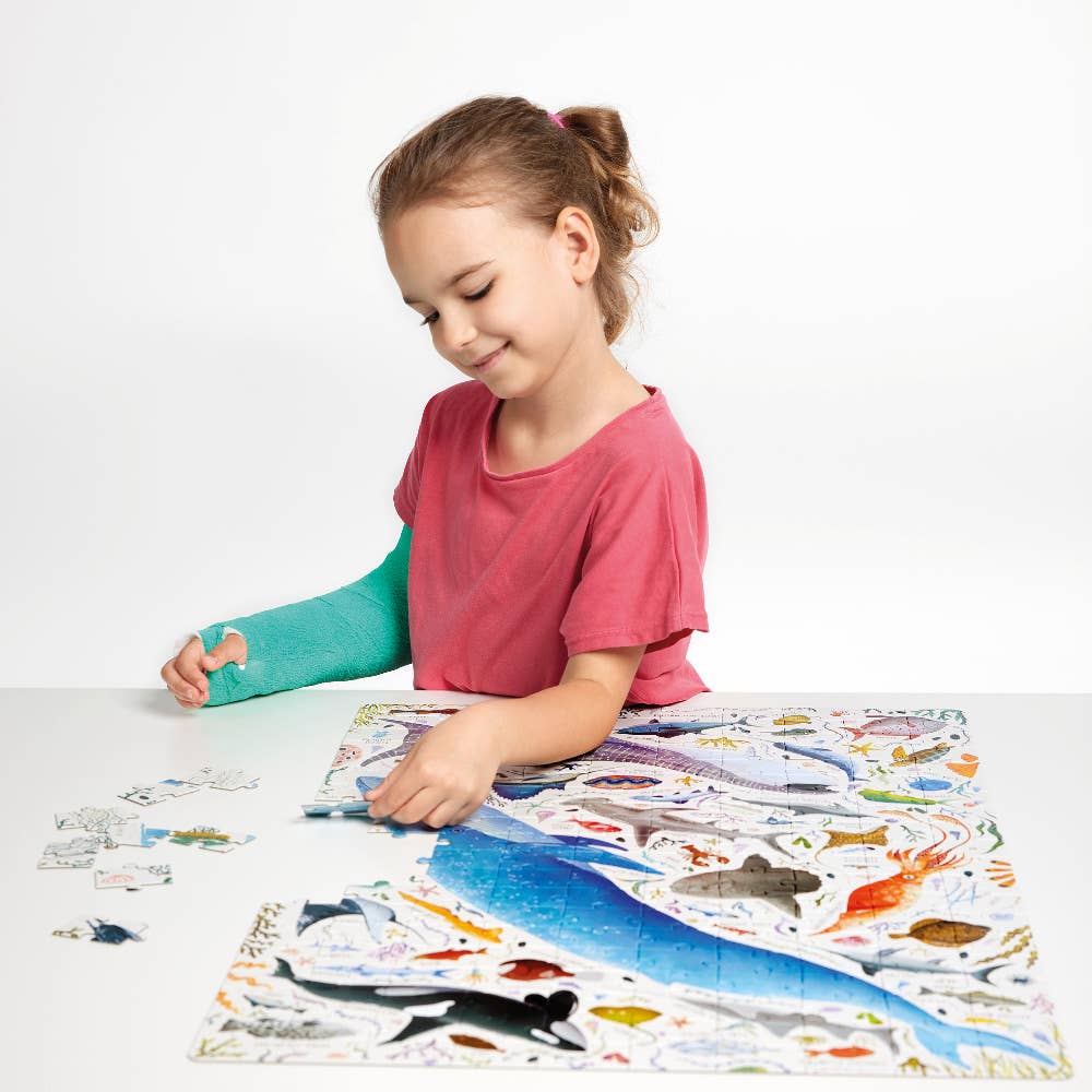 Child with a cast playing with a colorful animal-themed mat on a white background