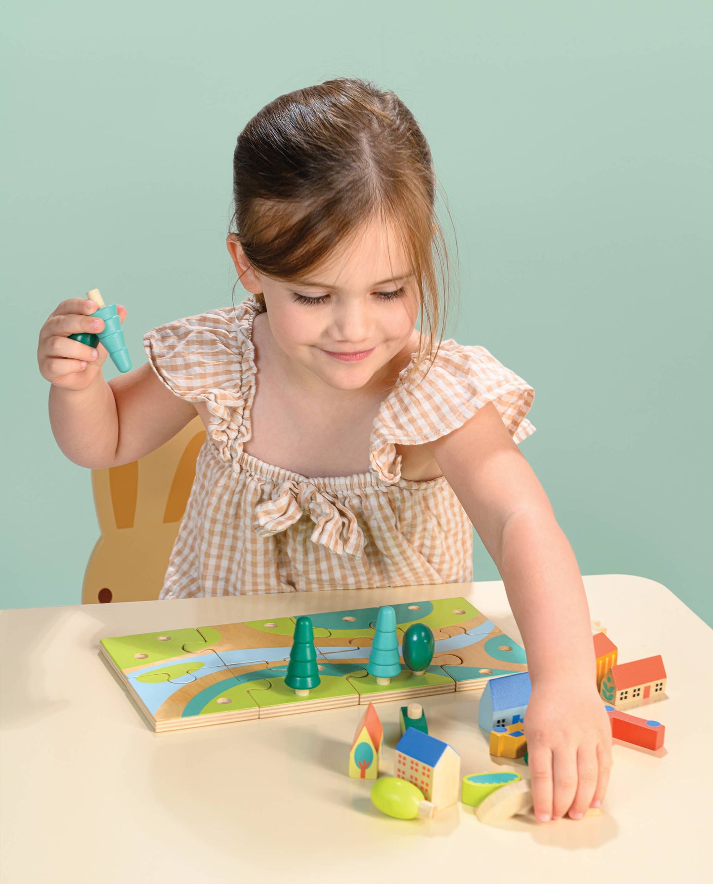 Young girl playing with a wooden toy set on a light blue background