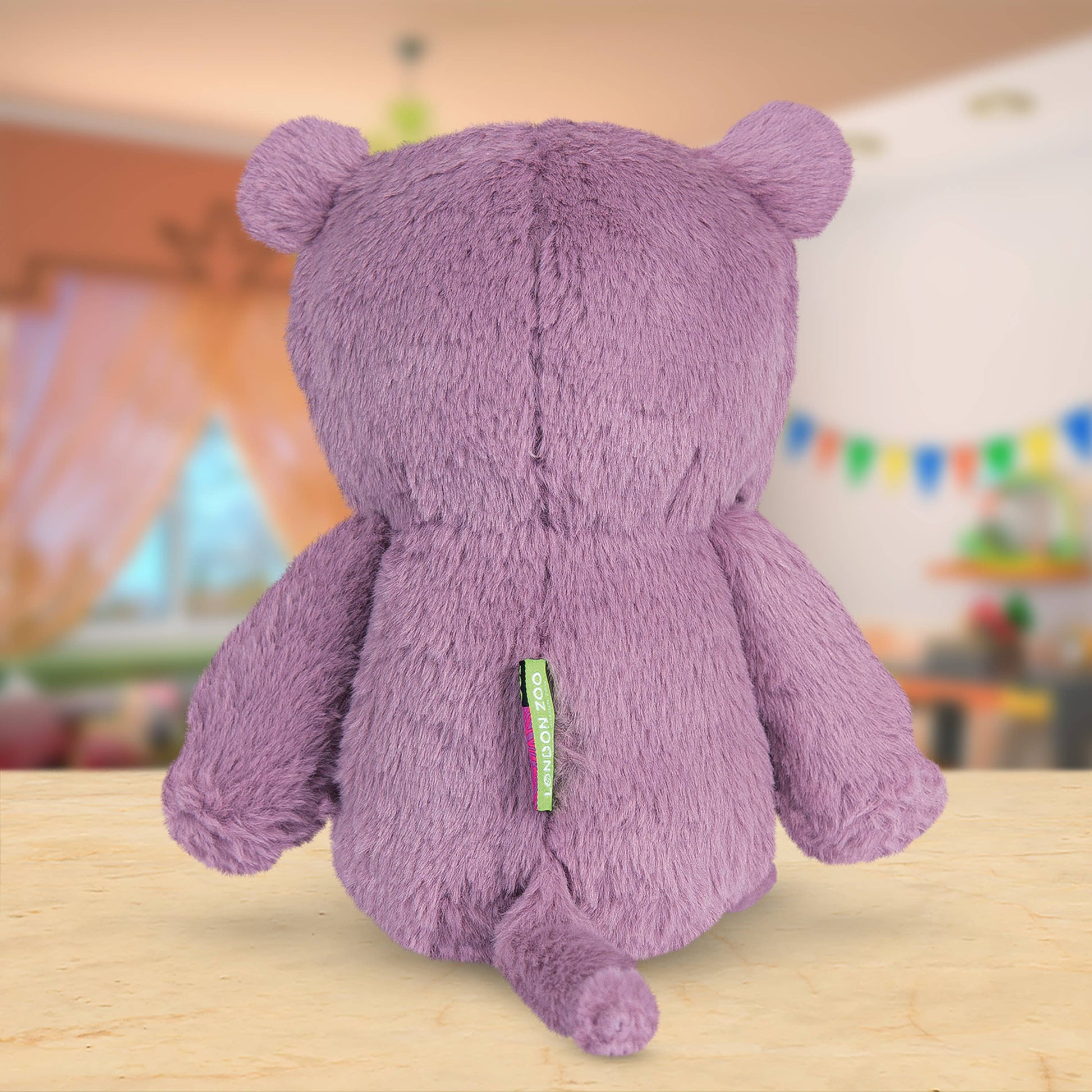 Back of purple hippo with a visible tag on a wooden surface, blurred indoor background