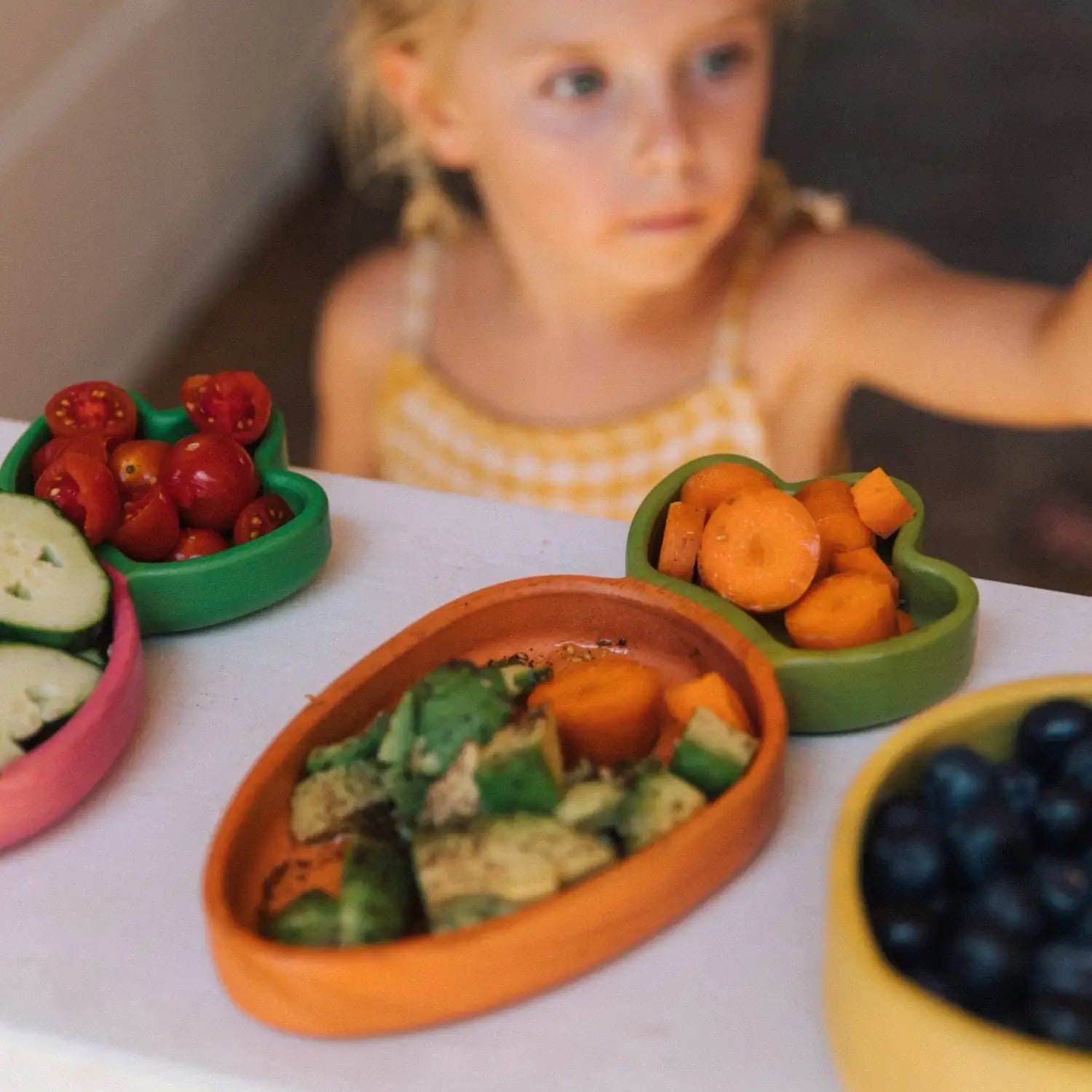 Colorful toy food set on a table with a child in the background