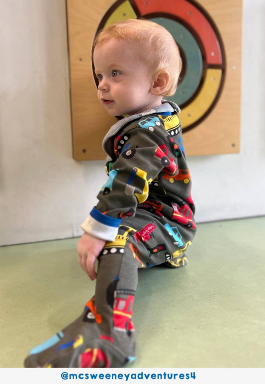 Child wearing a colorful onesie with a wooden wall and target in the background