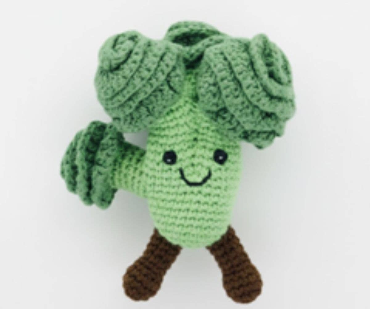 Crocheted green broccoli toy with a smiling face on a white background