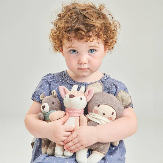 Child holding three stuffed animals against a plain background