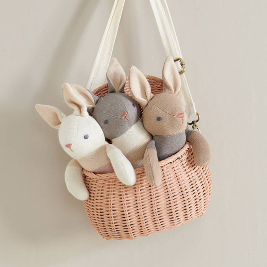 Wicker basket with plush bunny toys on a neutral background