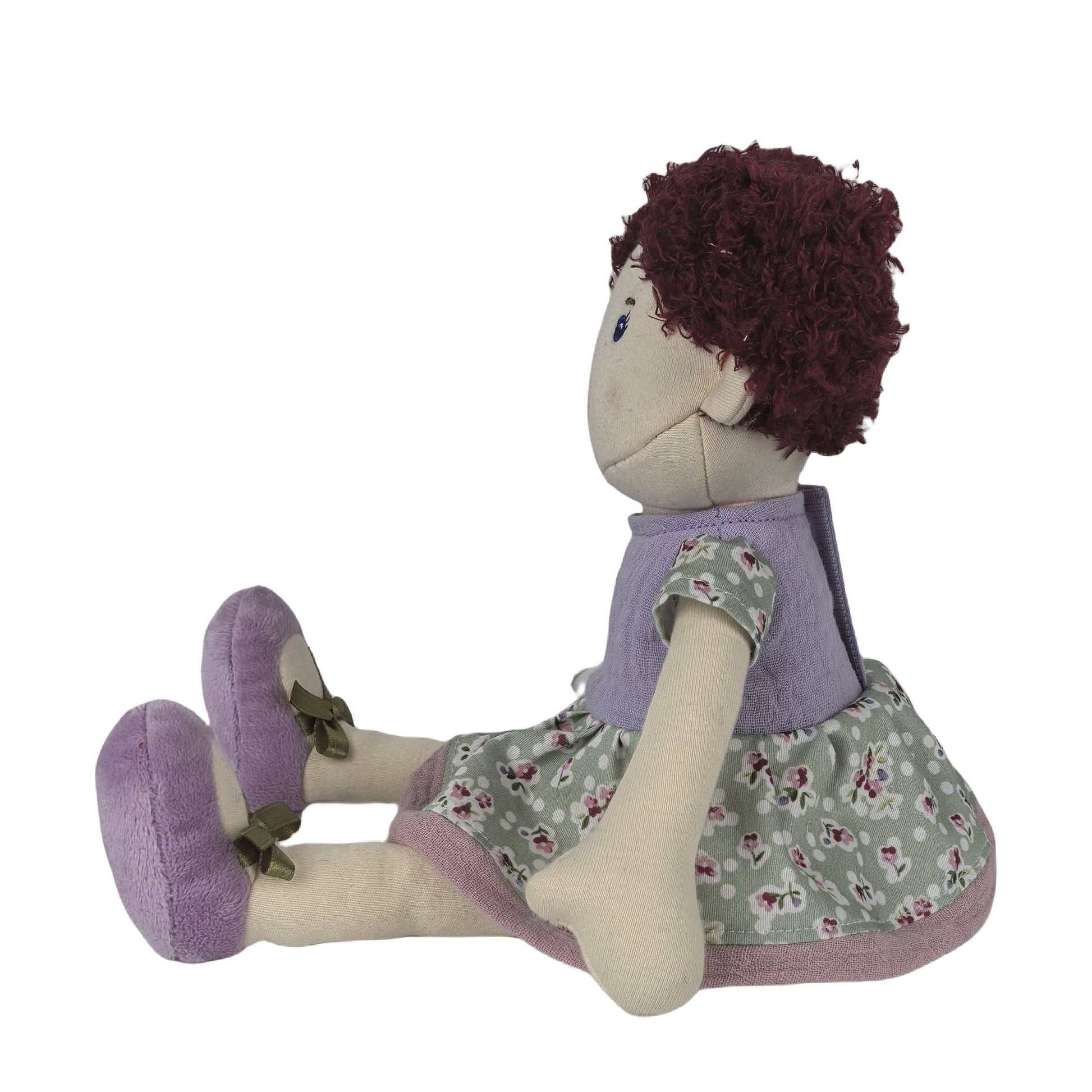 Stuffed doll with purple hair, floral dress, and purple shoes on a white background