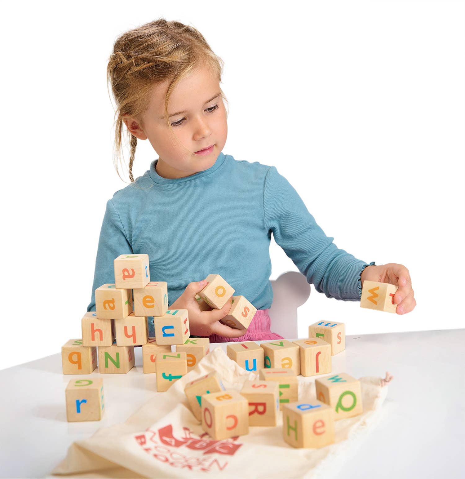 Child playing with wooden alphabet blocks on a white background