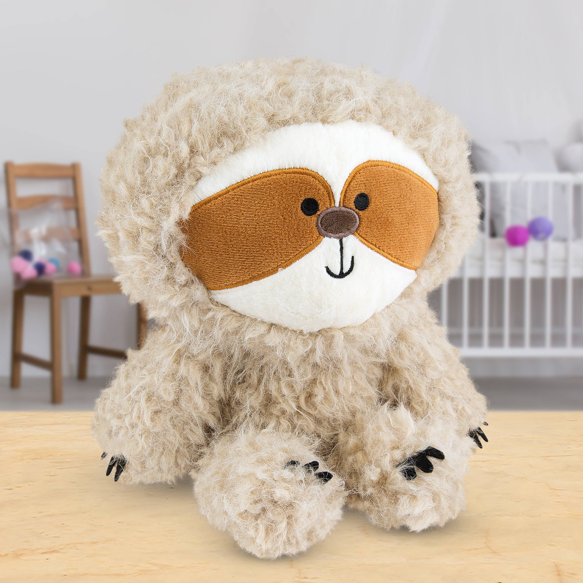 Plush sloth toy on a wooden surface in a room setting