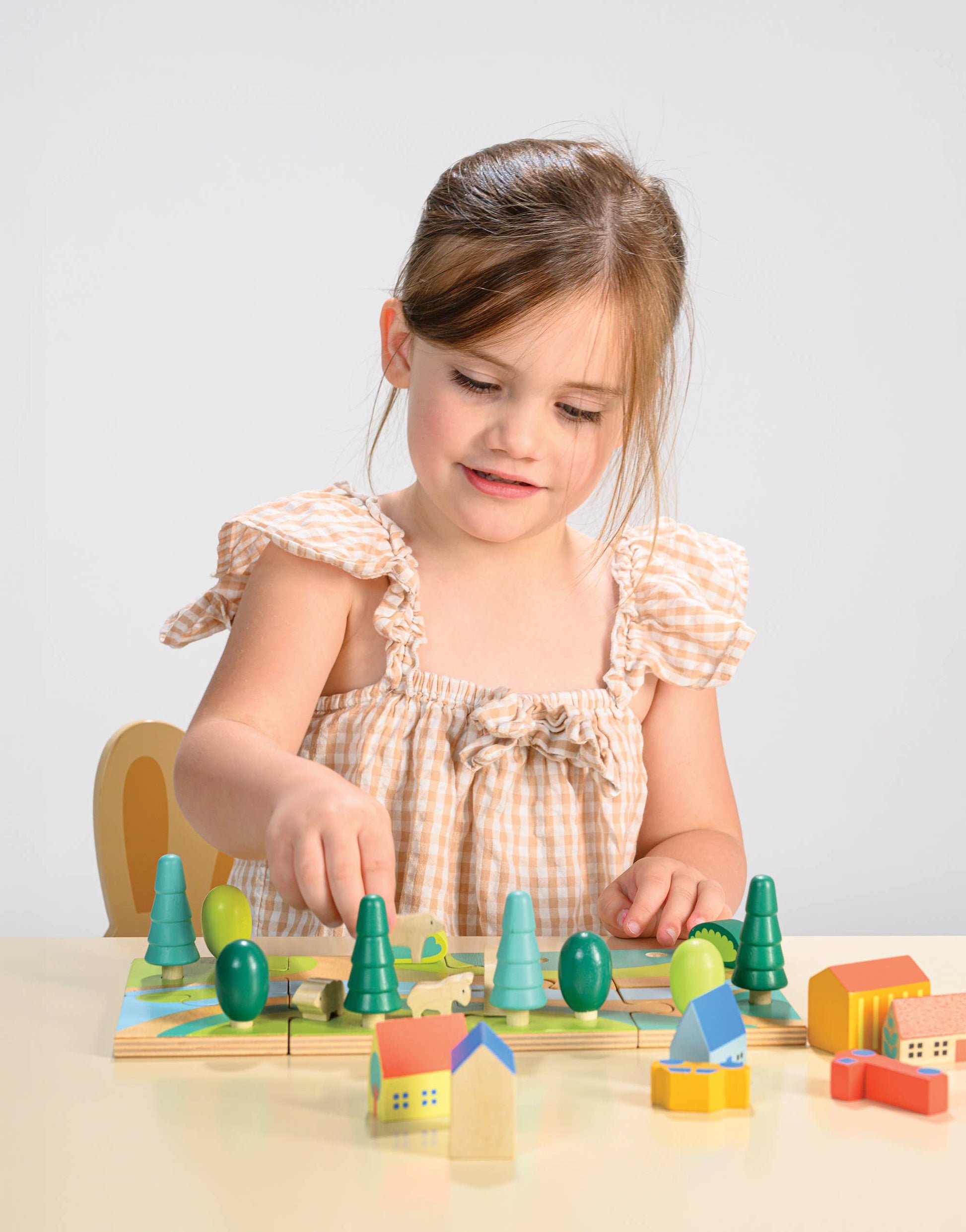 Young girl playing with a wooden toy set on a light surface.